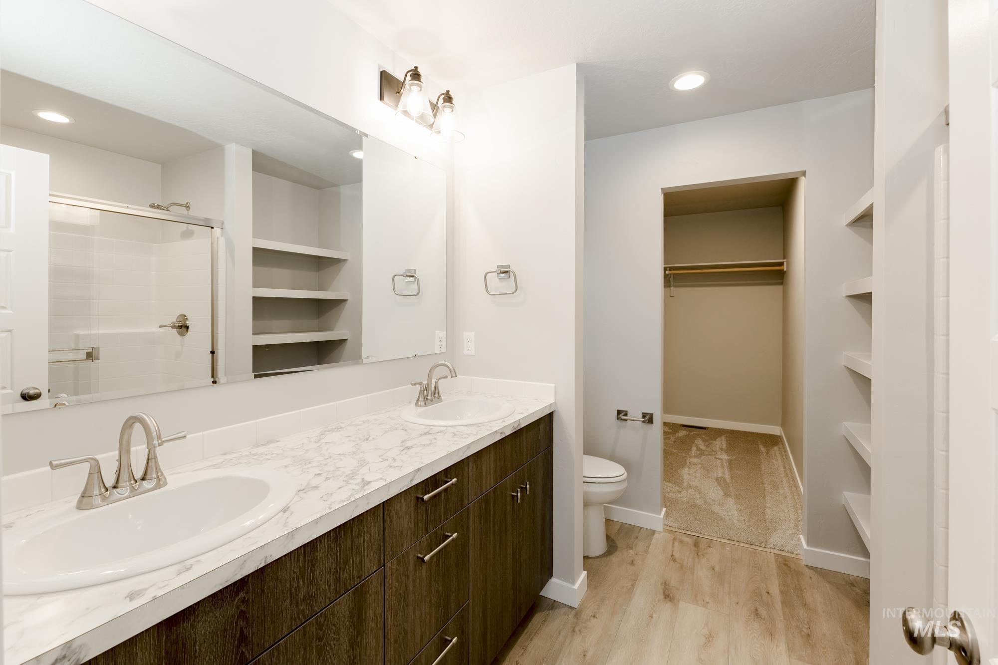 Bathroom featuring a spacious closet, a stall shower, double vanity, built in shelves, and recessed lighting