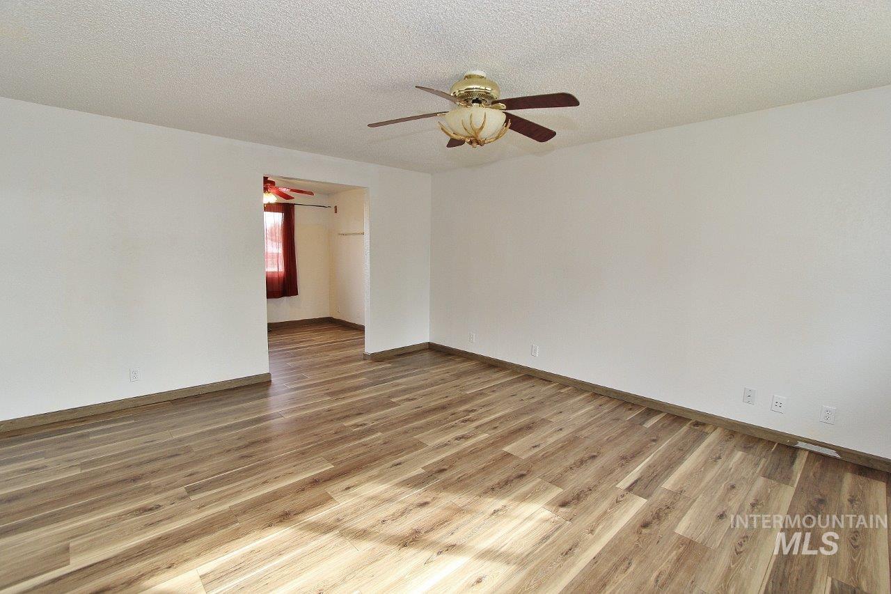 Unfurnished room featuring light wood-style flooring, a textured ceiling, and ceiling fan