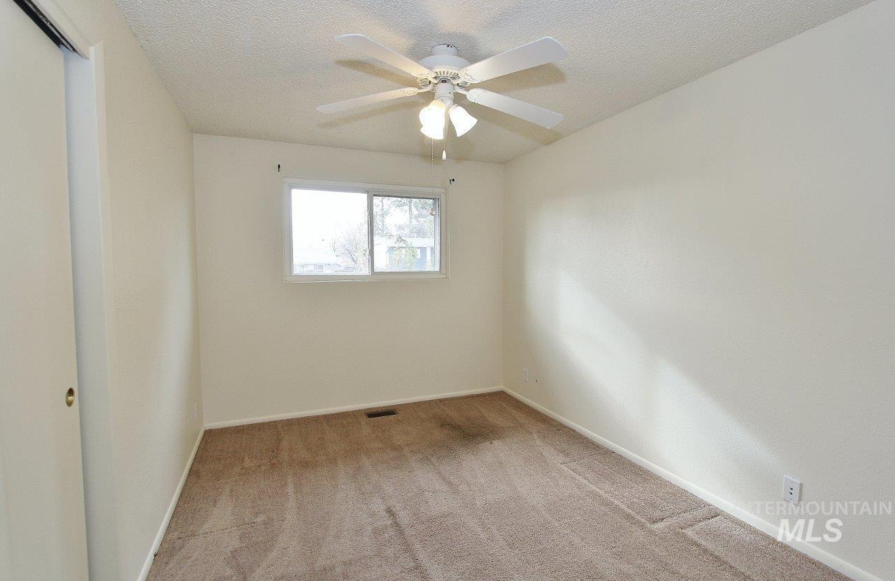 Spare room featuring light colored carpet, a textured ceiling, and ceiling fan