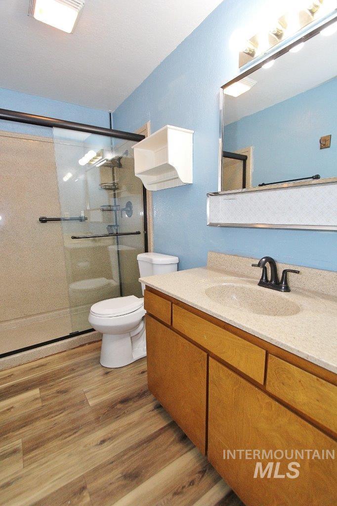 Bathroom featuring vanity, light wood-style flooring, and a stall shower