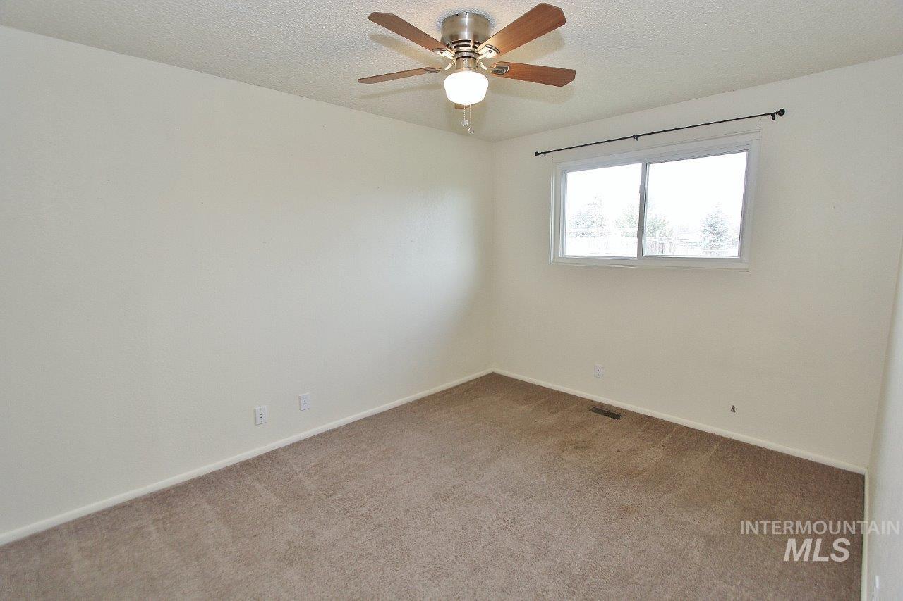 Empty room with a textured ceiling, carpet, and a ceiling fan