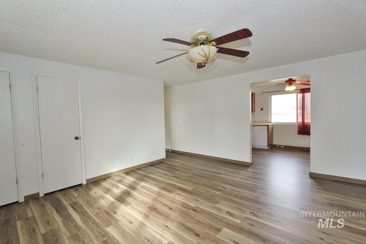 Empty room featuring light wood-type flooring, a textured ceiling, and a ceiling fan