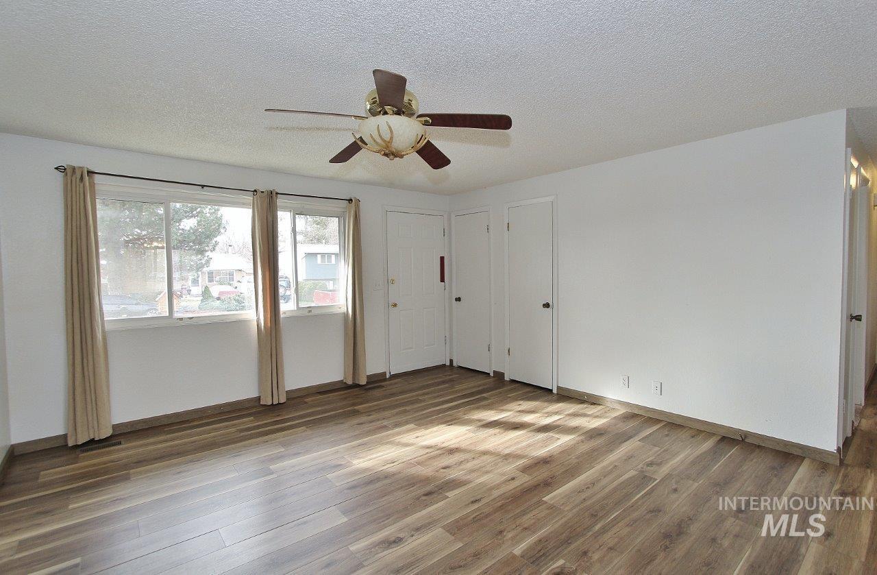 Empty room with light wood-type flooring, a textured ceiling, and ceiling fan