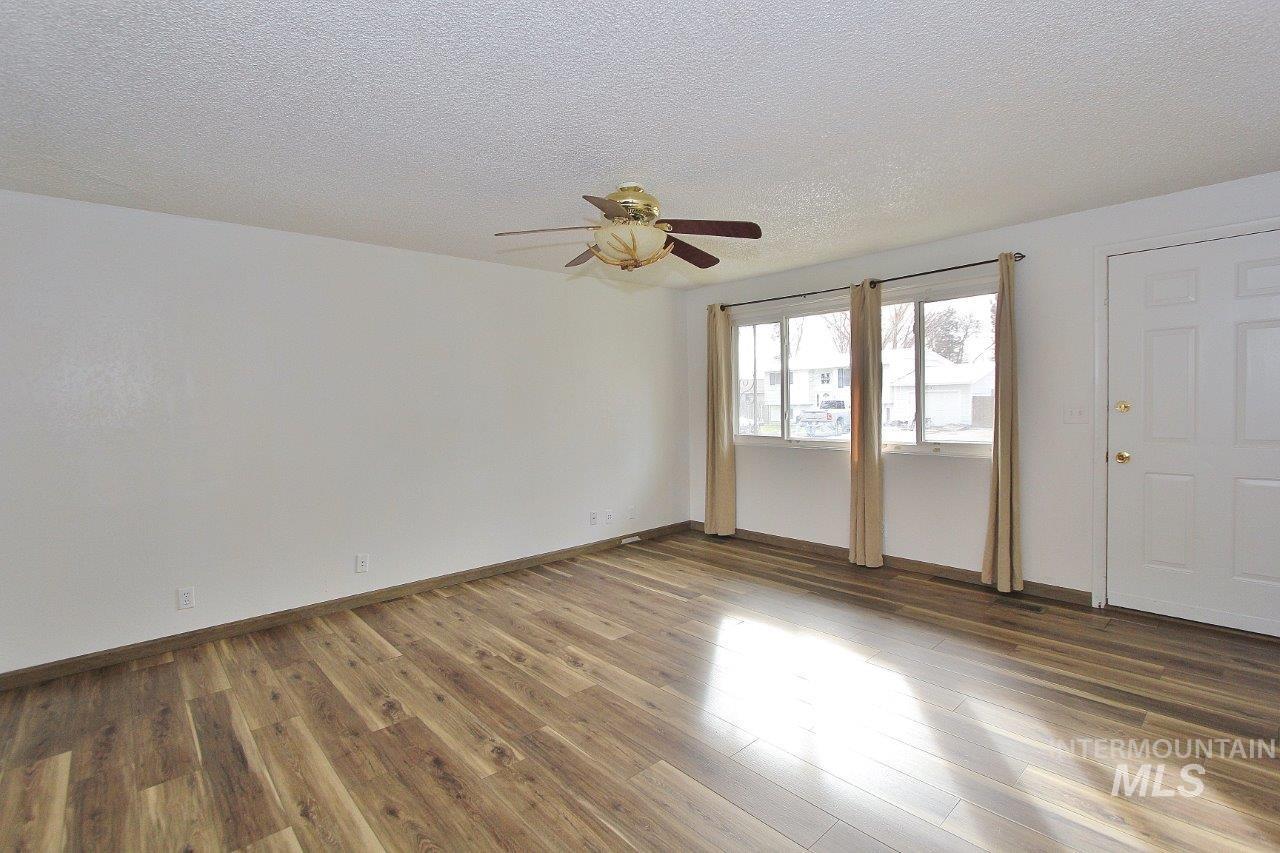 Unfurnished room with a textured ceiling, wood finished floors, and a ceiling fan