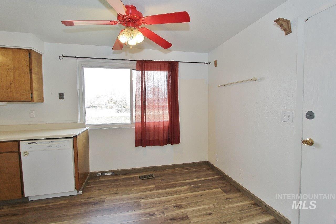 Kitchen with white dishwasher, brown cabinetry, light countertops, dark wood-style flooring, and a ceiling fan