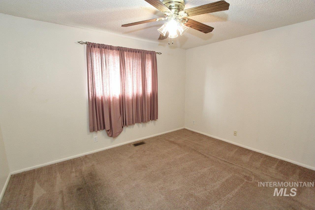 Carpeted spare room with a textured ceiling and a ceiling fan