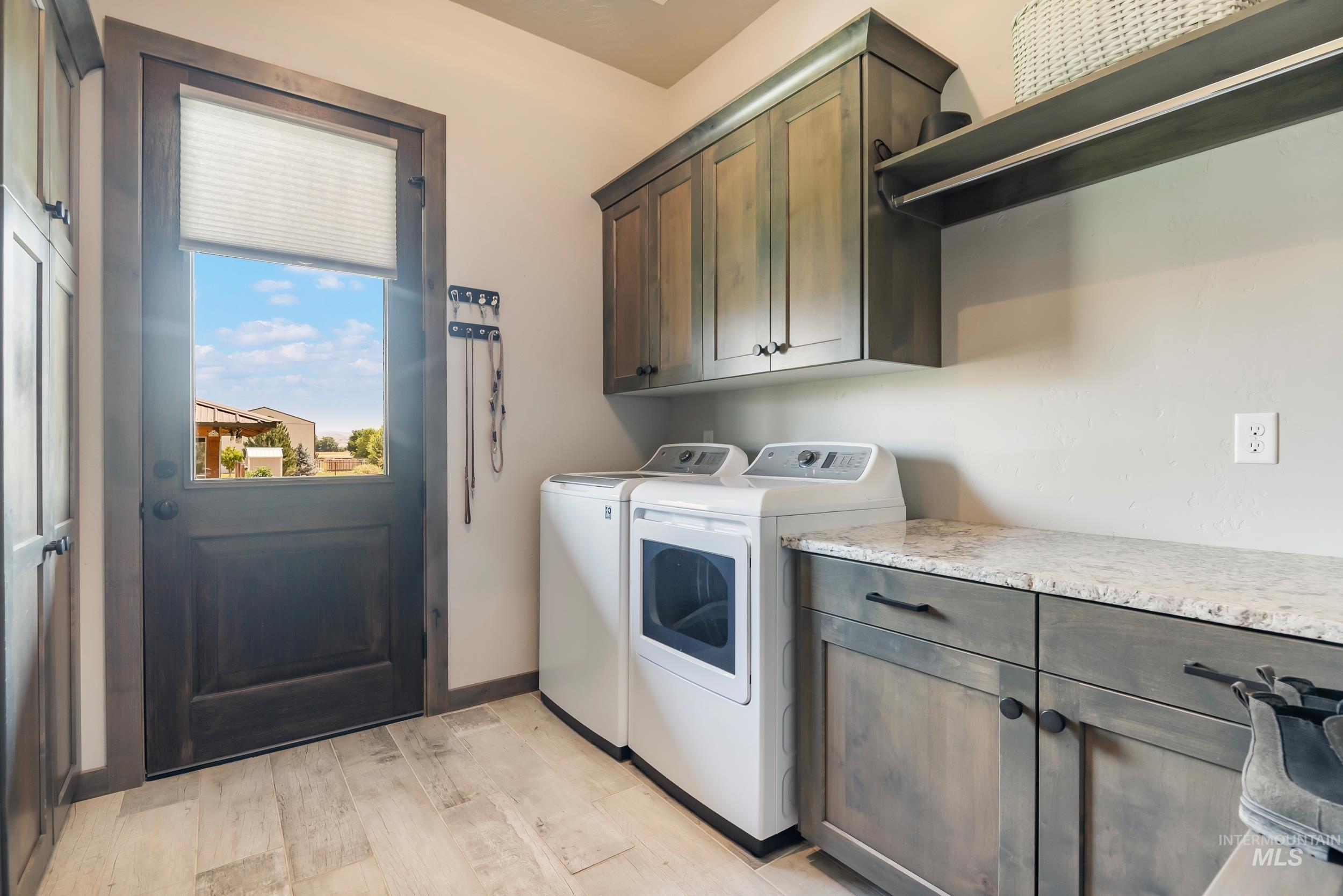 Laundry area with cabinet space, separate washer and dryer, and light wood-type flooring