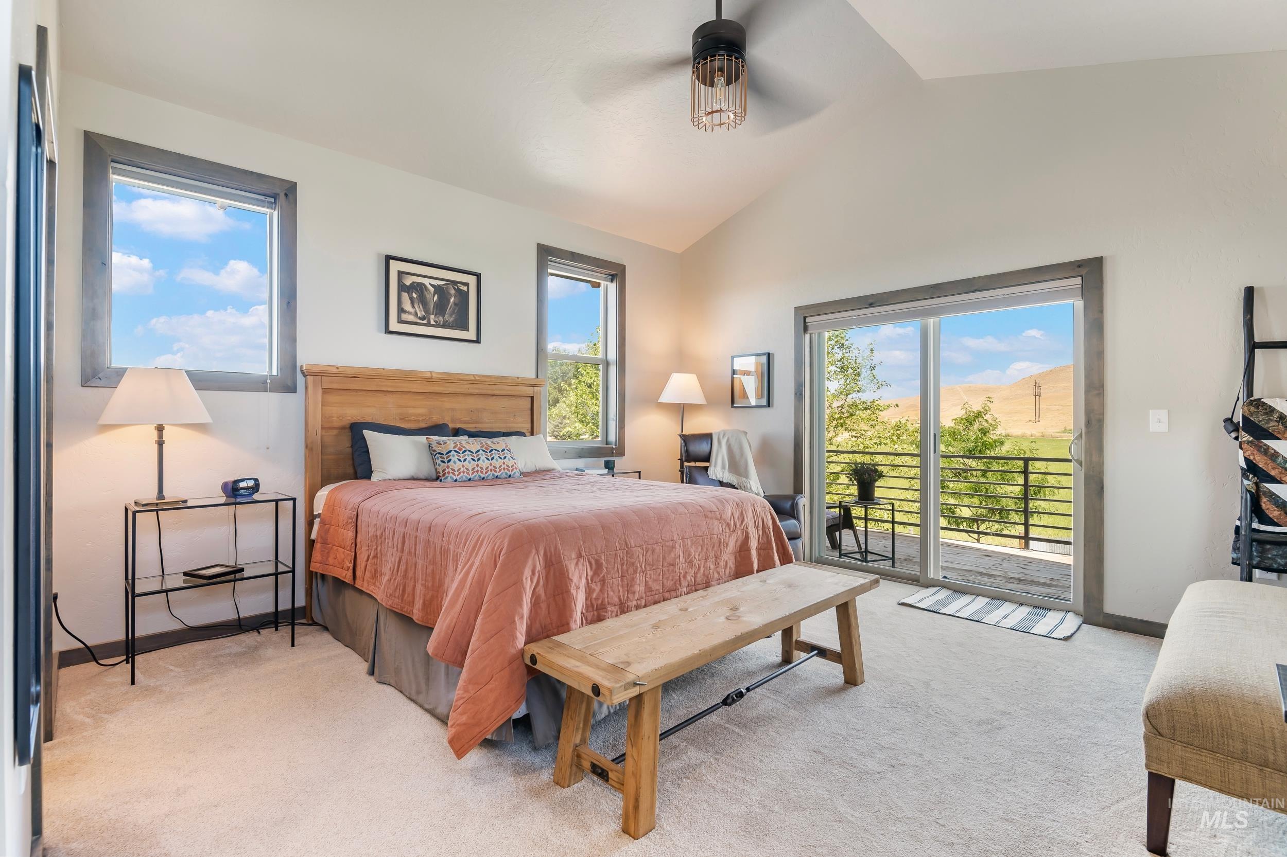 Bedroom featuring light carpet, access to exterior, vaulted ceiling, and a ceiling fan