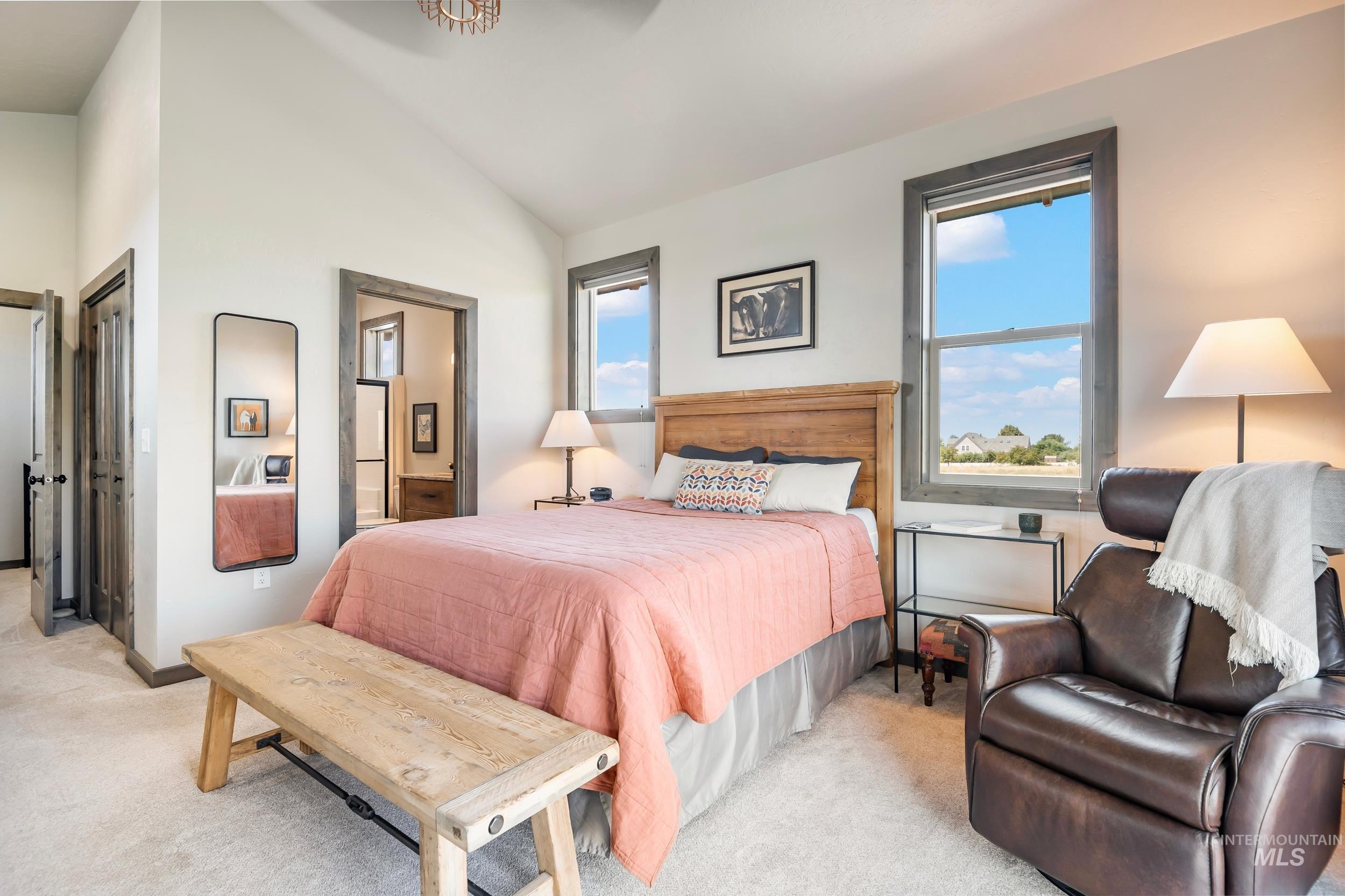 Bedroom featuring light carpet, ensuite bath, and high vaulted ceiling