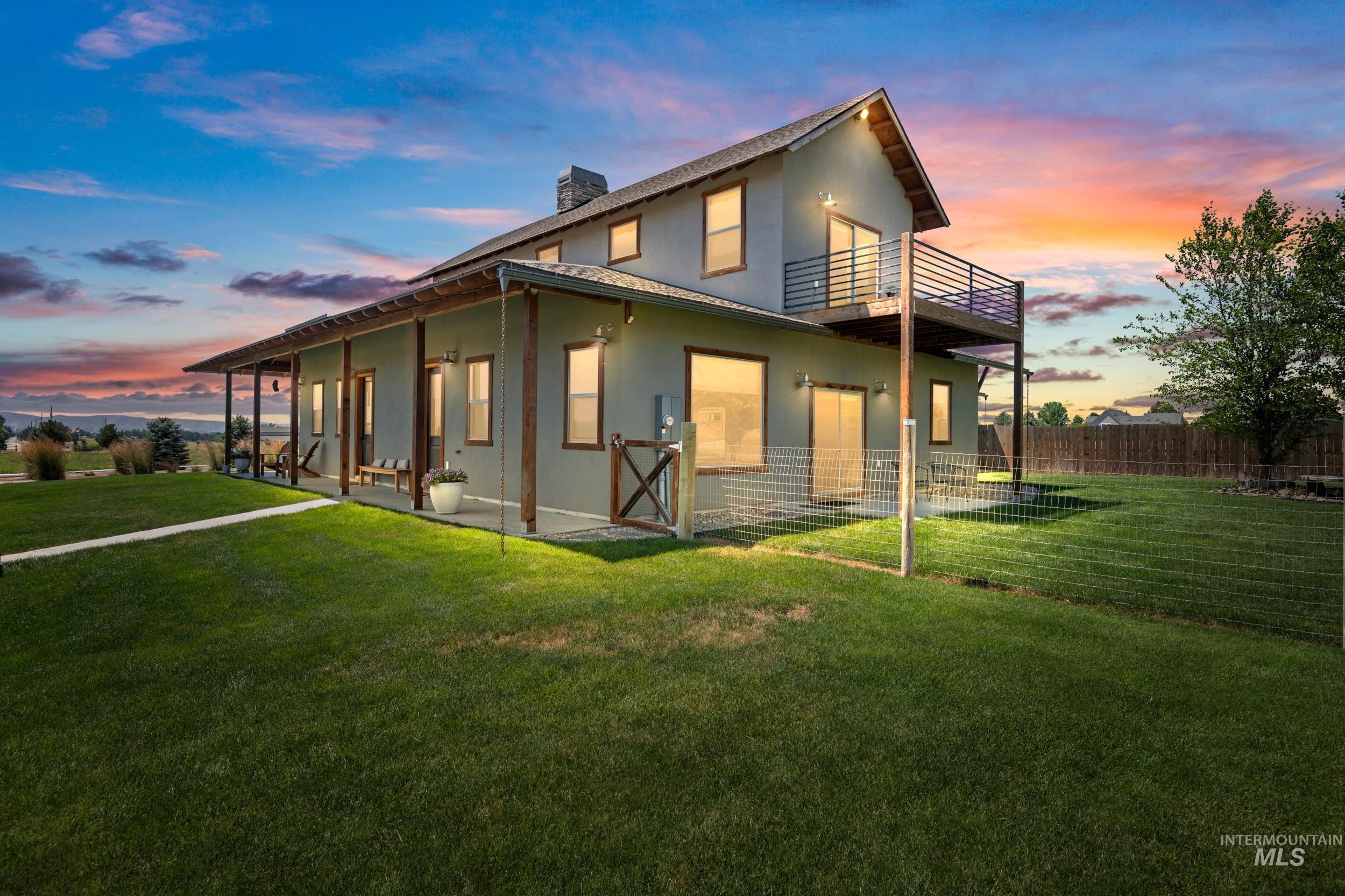 Rear view of property with a balcony, stucco siding, a chimney, and a patio