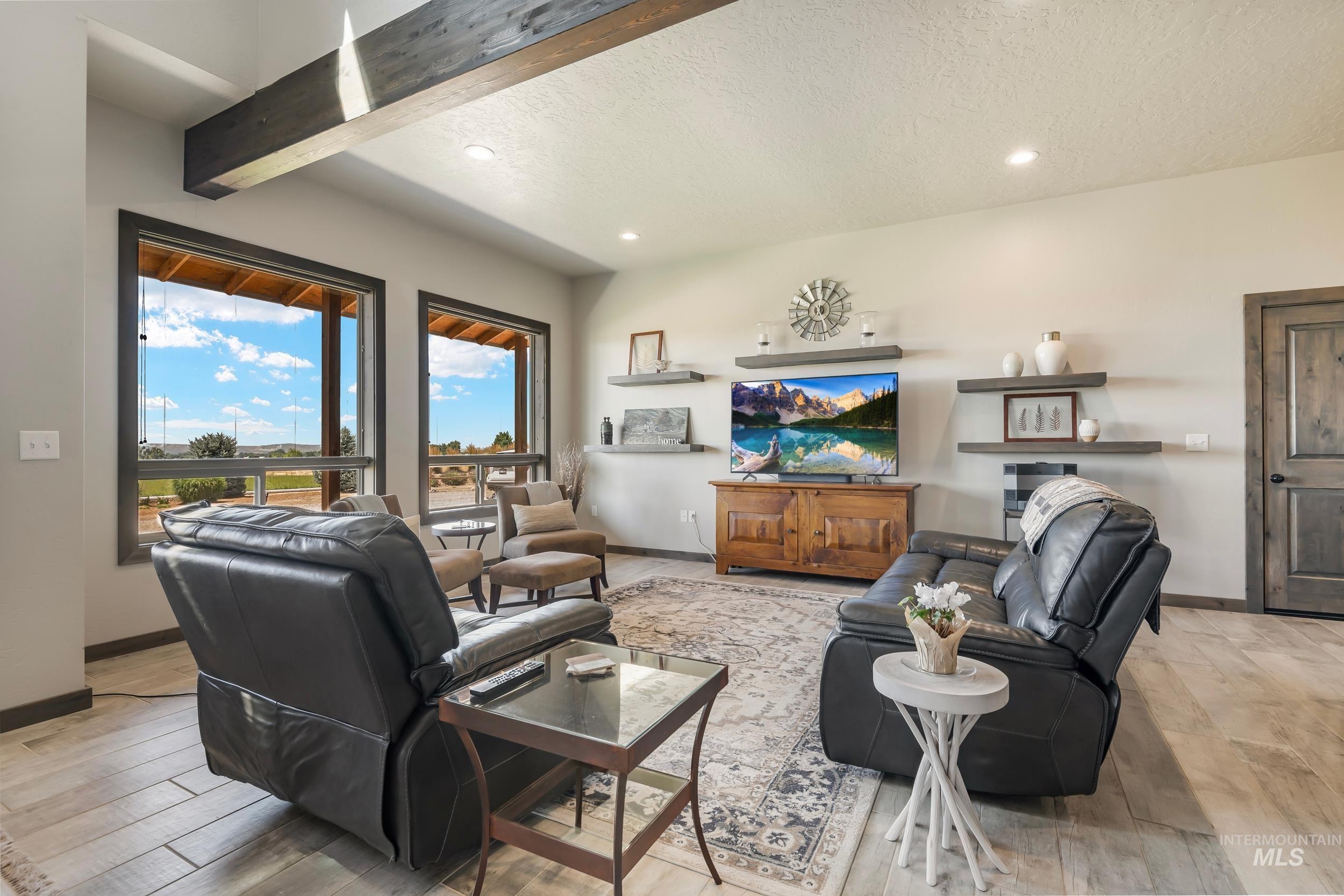 Living room with a textured ceiling, recessed lighting, light wood-style flooring, and beam ceiling