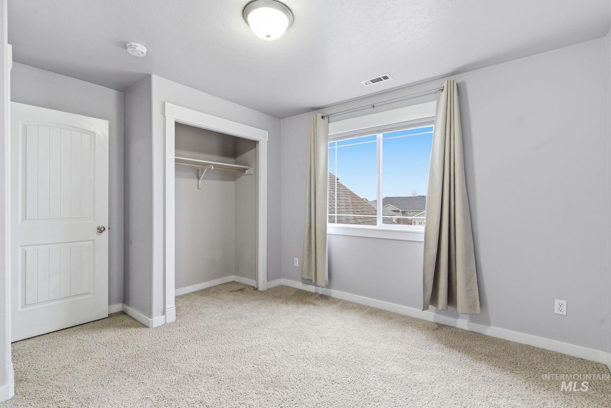 Unfurnished bedroom with light carpet and a closet