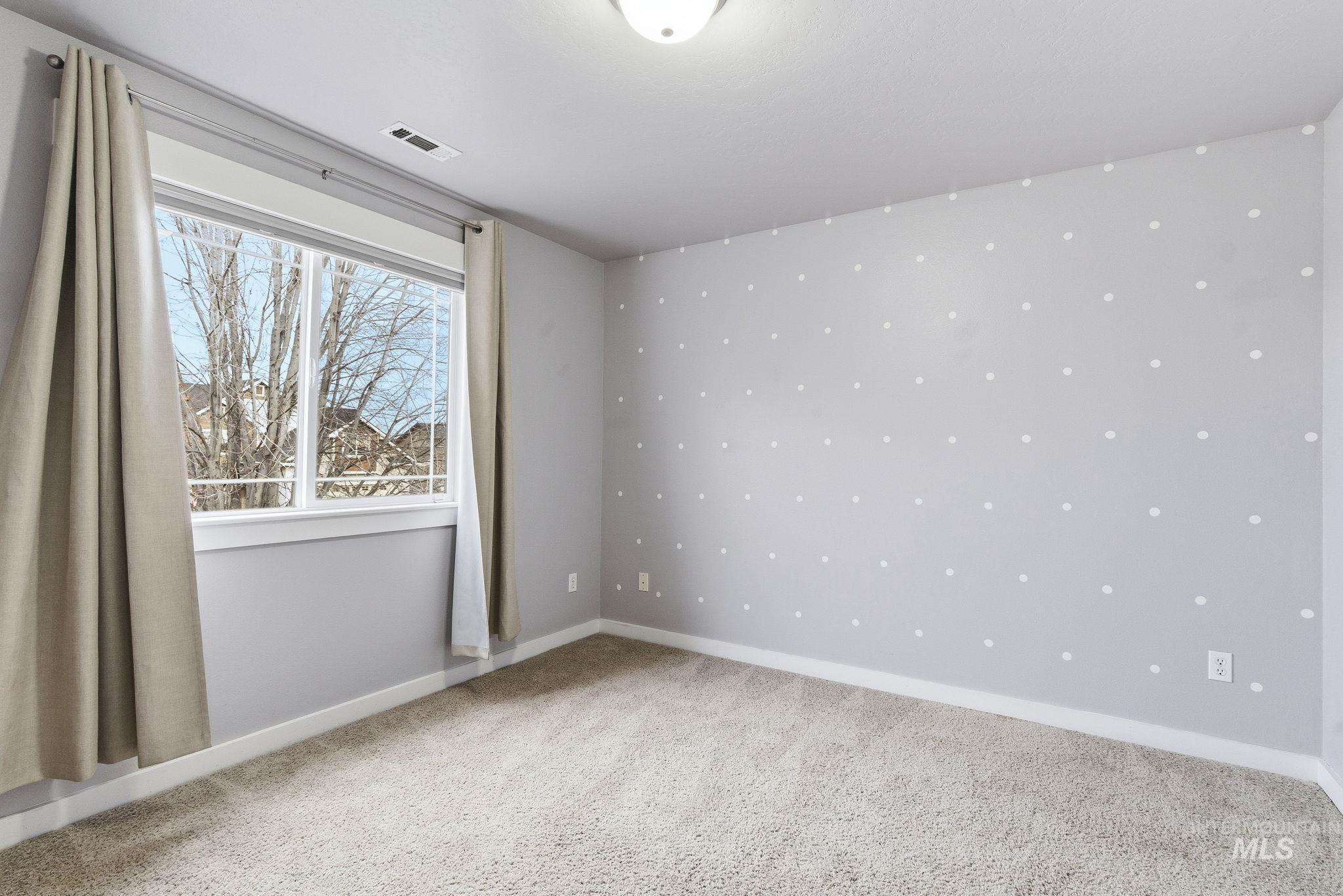 Empty room with light colored carpet and baseboards