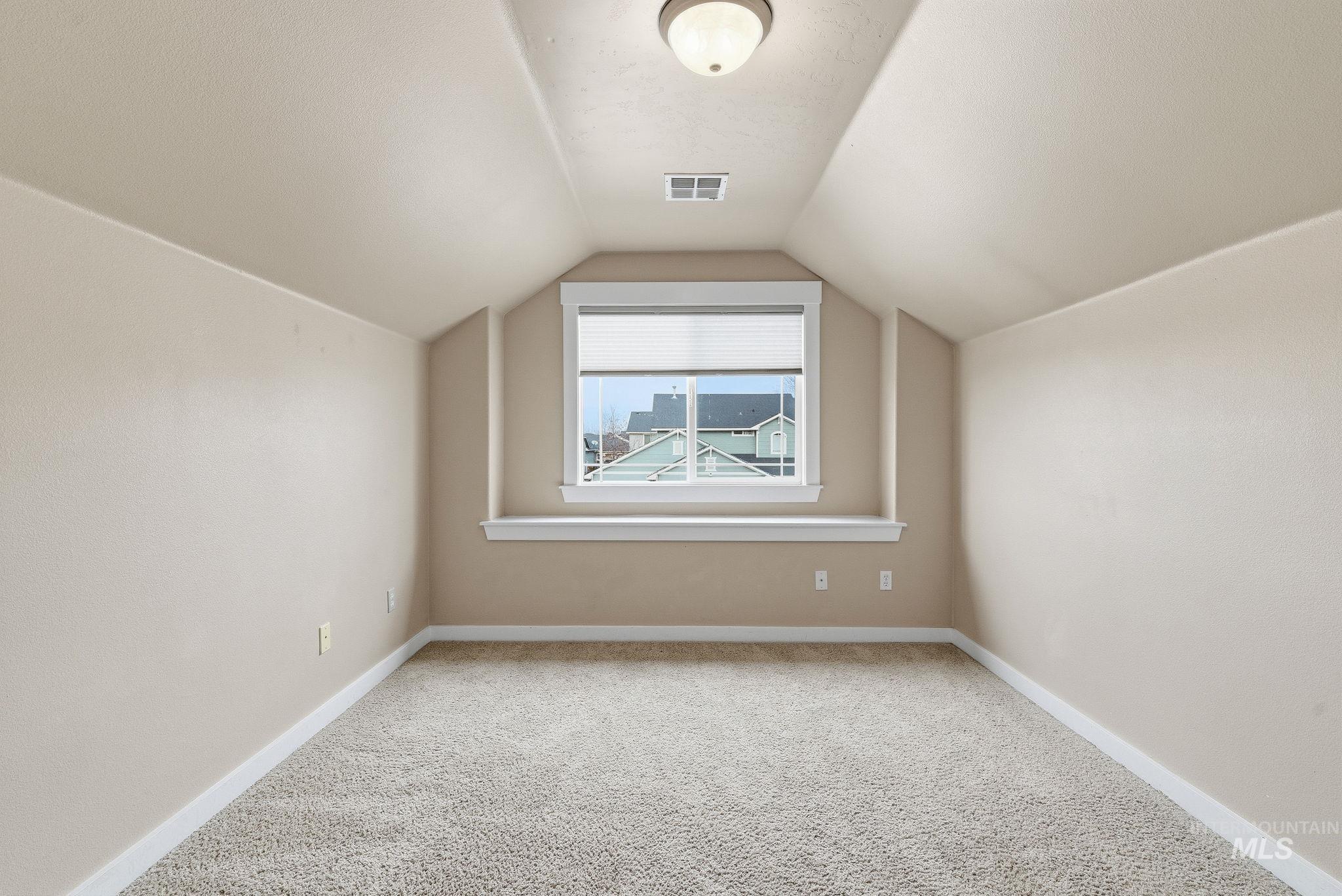 Additional living space with carpet and vaulted ceiling