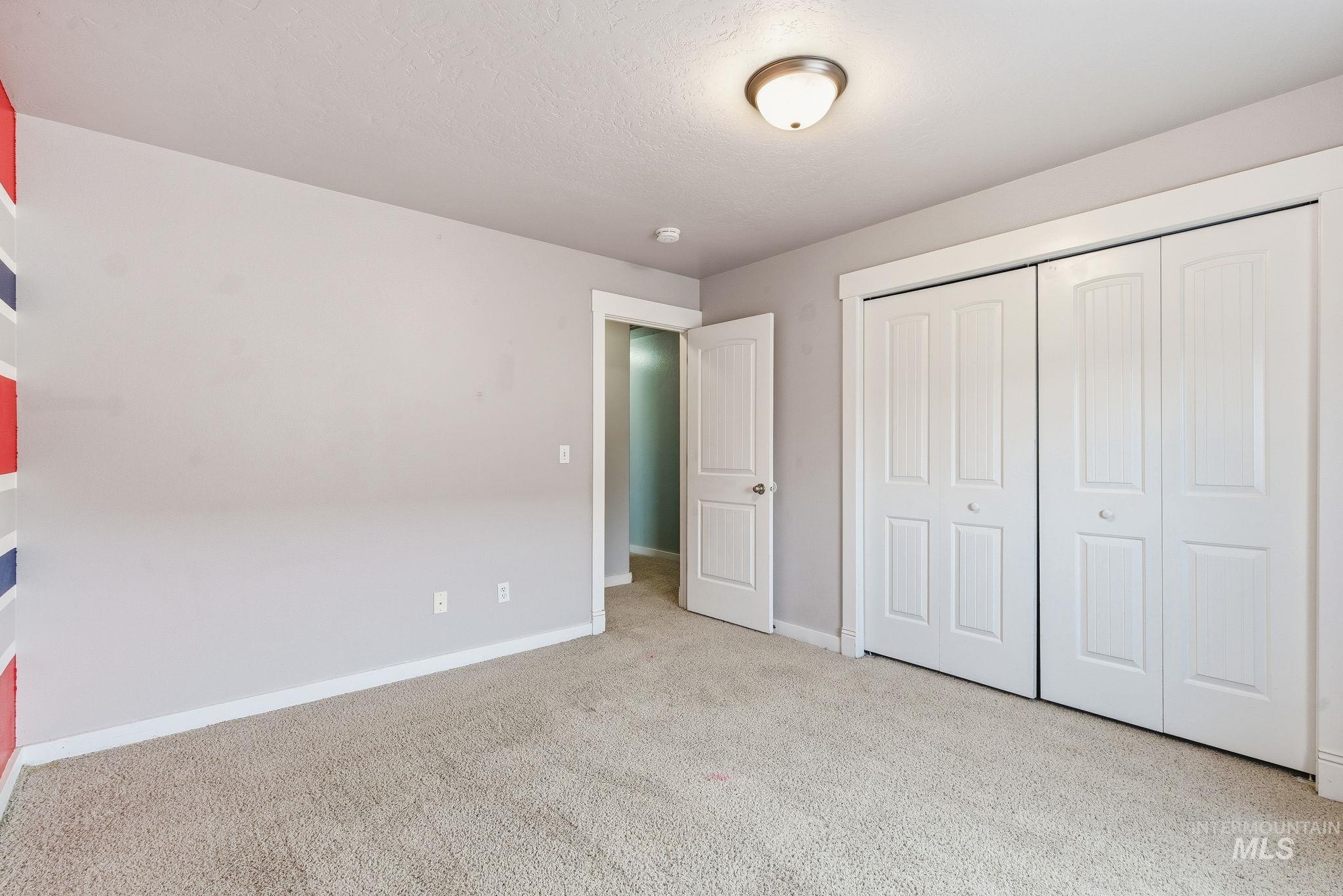 Unfurnished bedroom with light colored carpet, a closet, and a textured ceiling