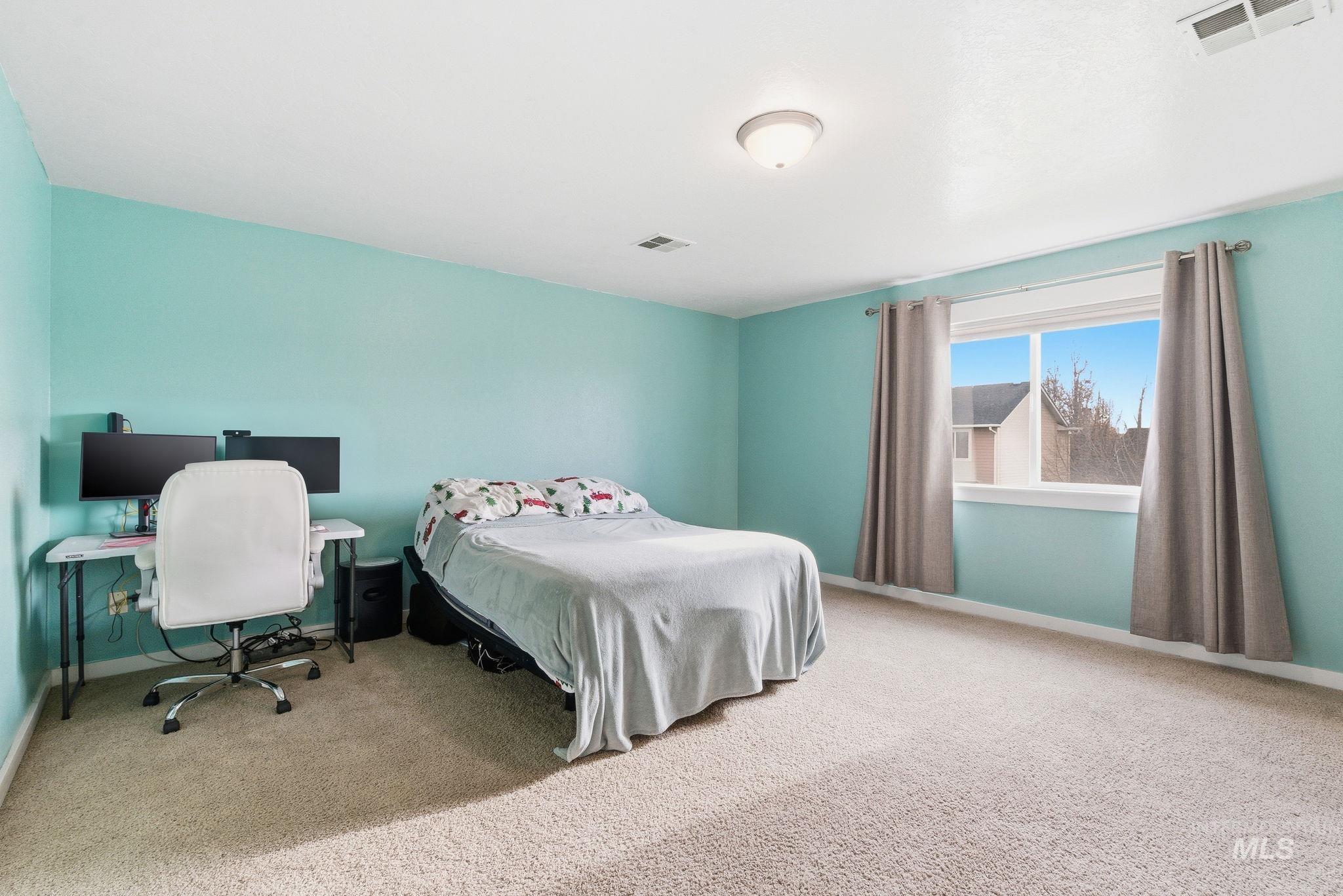 Carpeted bedroom featuring baseboards and an office area