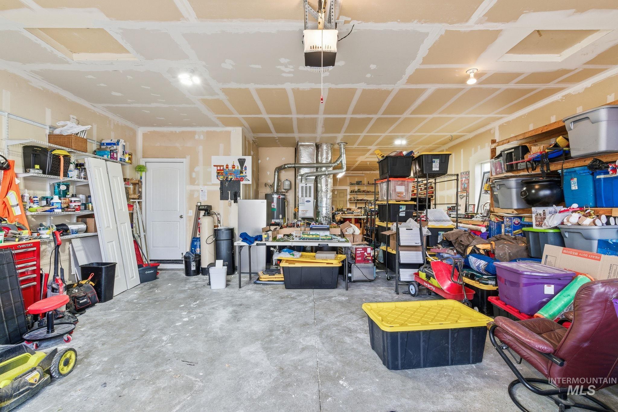 Garage featuring a workshop area, a garage door opener, and water heater
