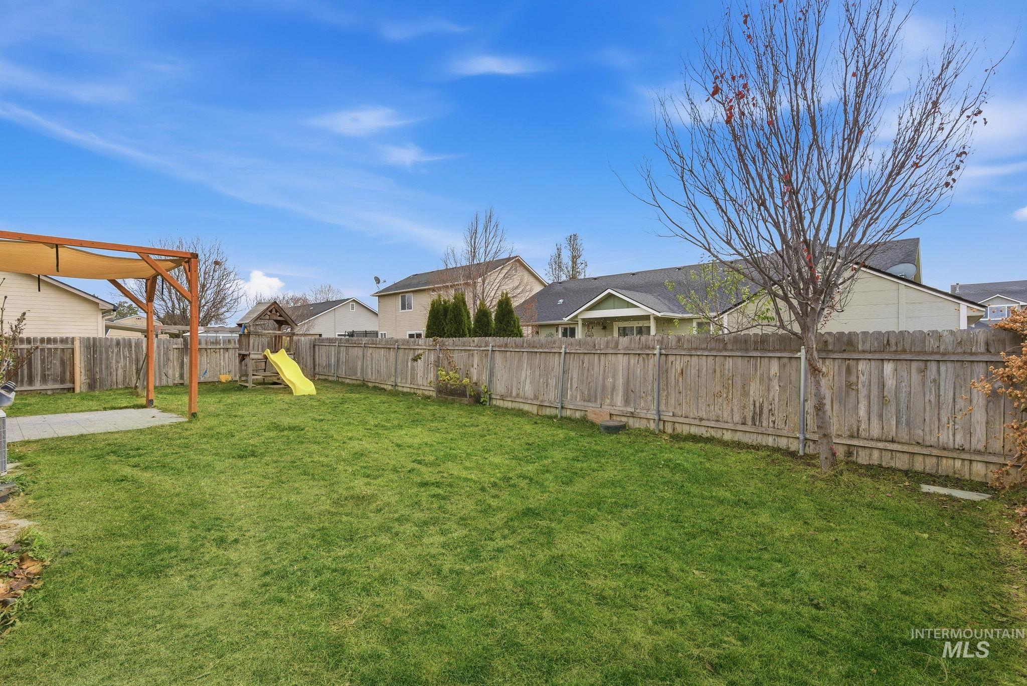 Fenced backyard with a residential view and a playground