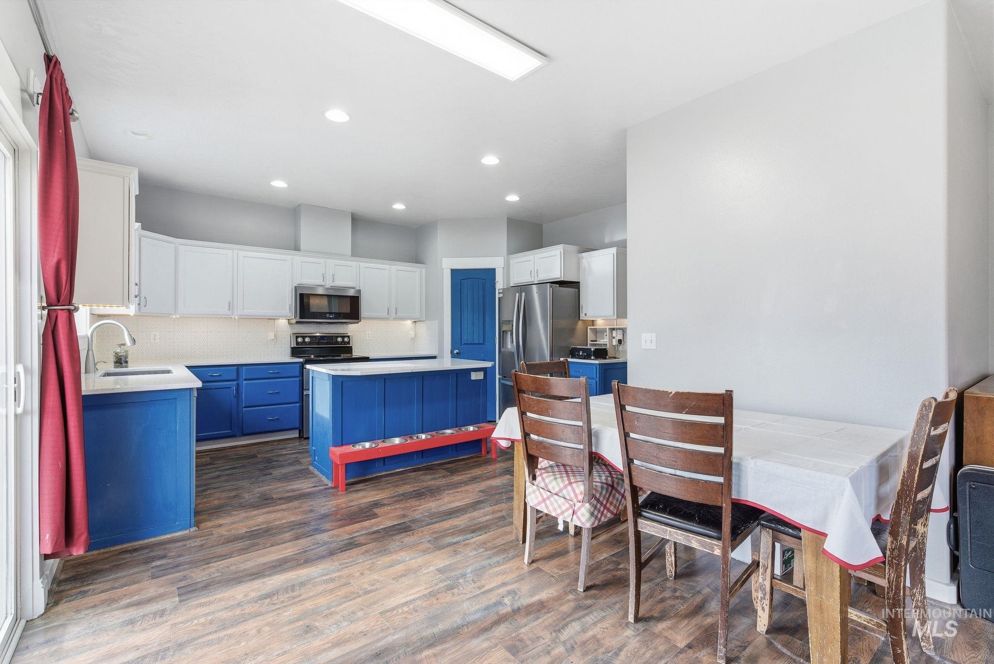 Kitchen featuring blue cabinets, white cabinetry, dark wood-style flooring, stainless steel appliances, and recessed lighting