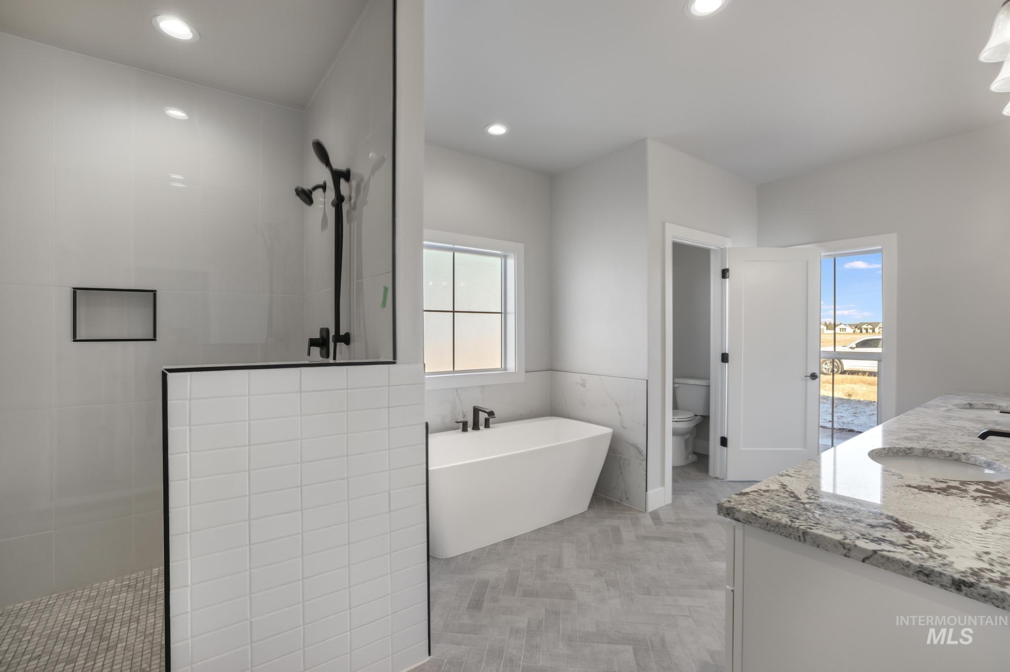 Bathroom with a freestanding tub, walk in shower, double vanity, recessed lighting, and wainscoting