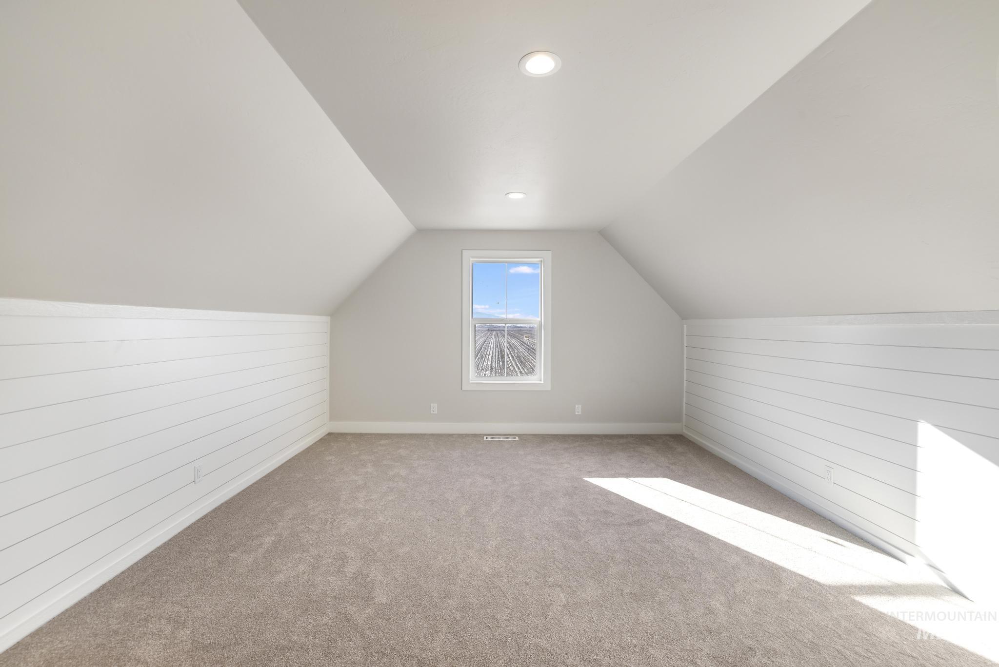 Bonus room with wooden walls, carpet flooring, and vaulted ceiling