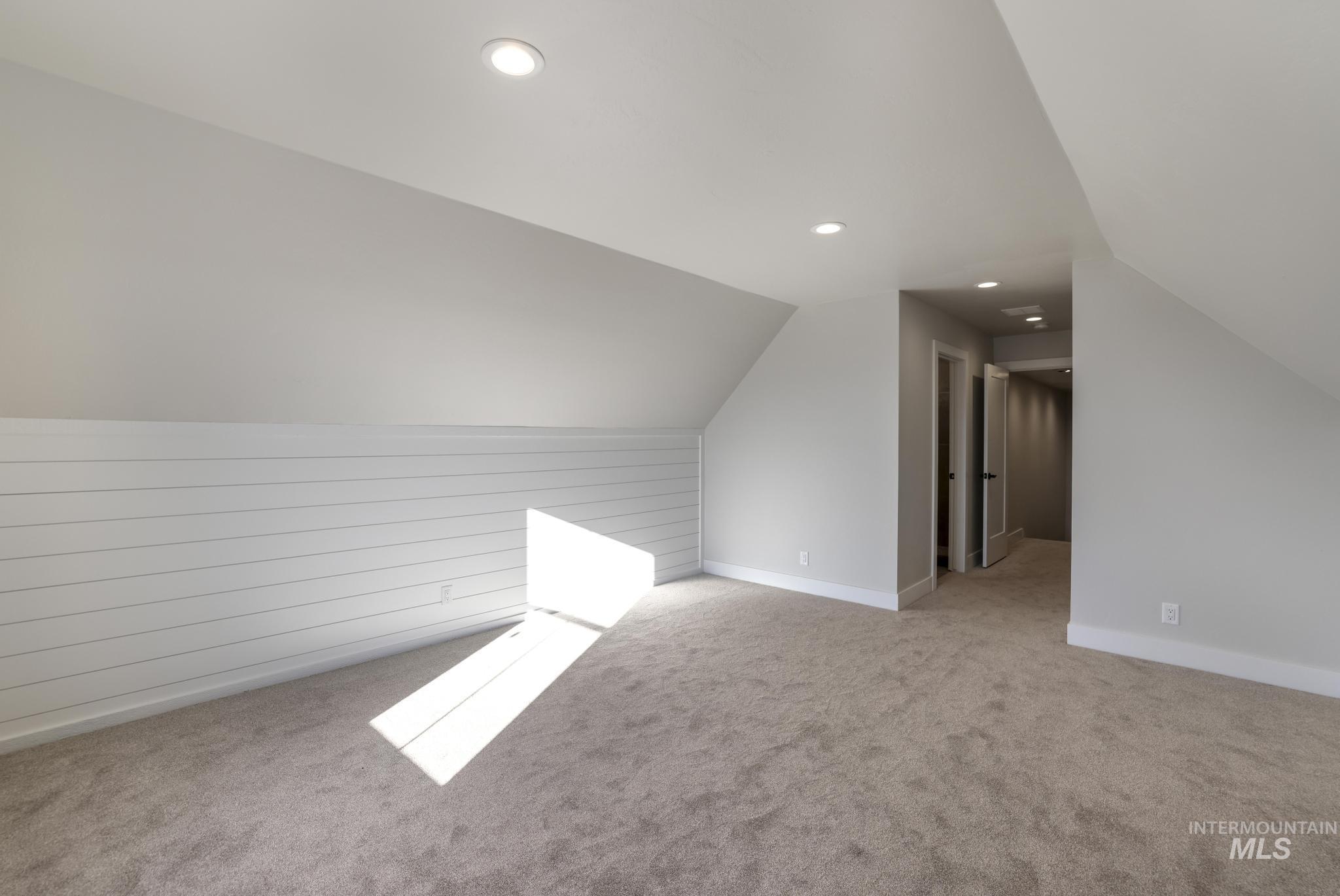 Bonus room featuring recessed lighting, light carpet, lofted ceiling, and wood walls