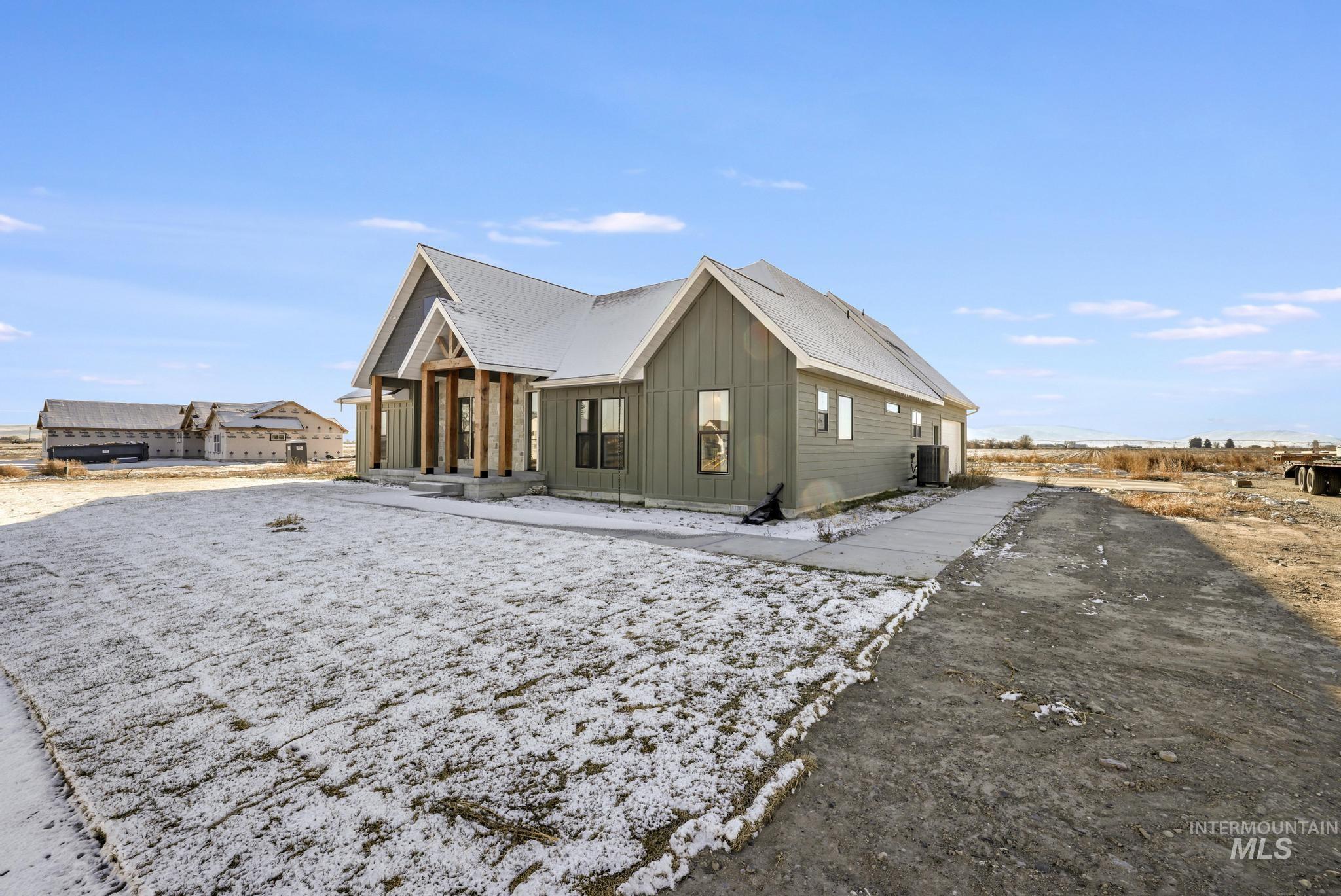 Snow covered property with board and batten siding and a cooling unit