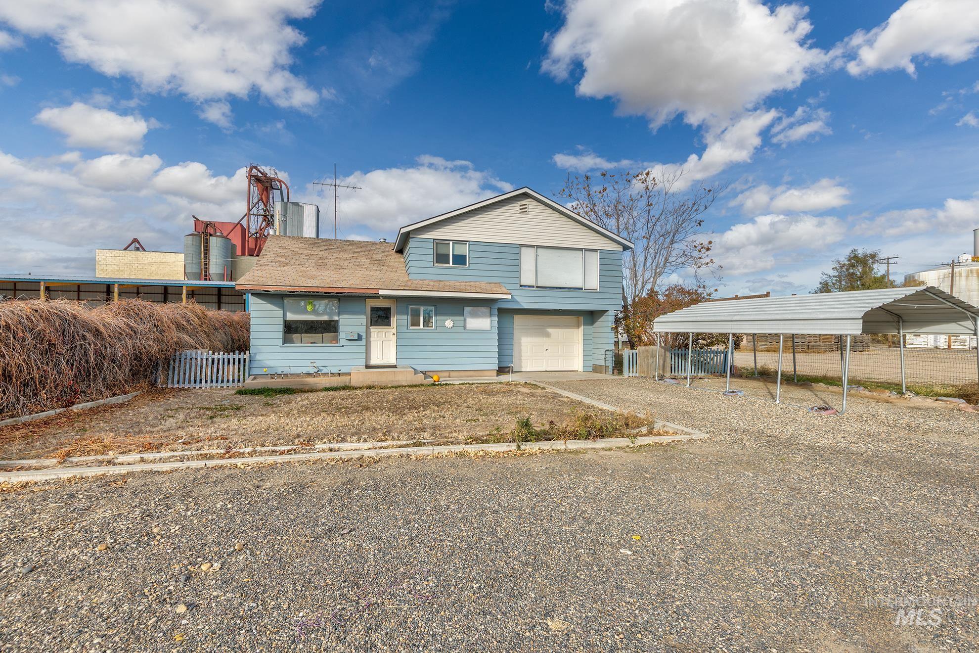 View of front of home with gravel driveway, a garage, and a detached carport