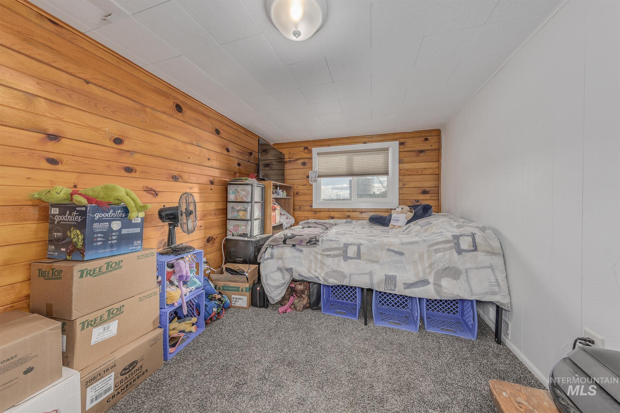 Carpeted bedroom featuring wooden walls