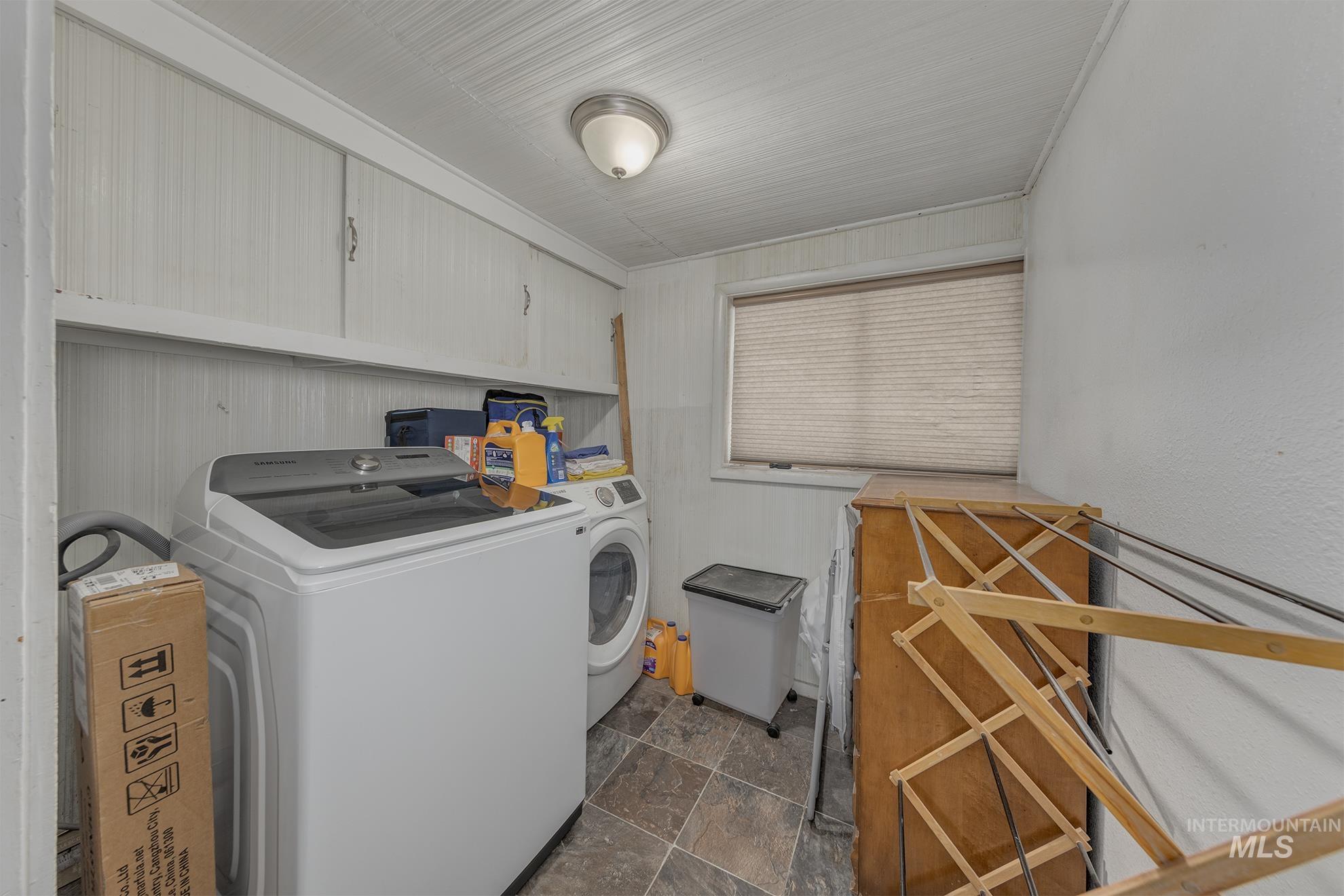 Laundry room with stone finish flooring, cabinet space, and washer and dryer