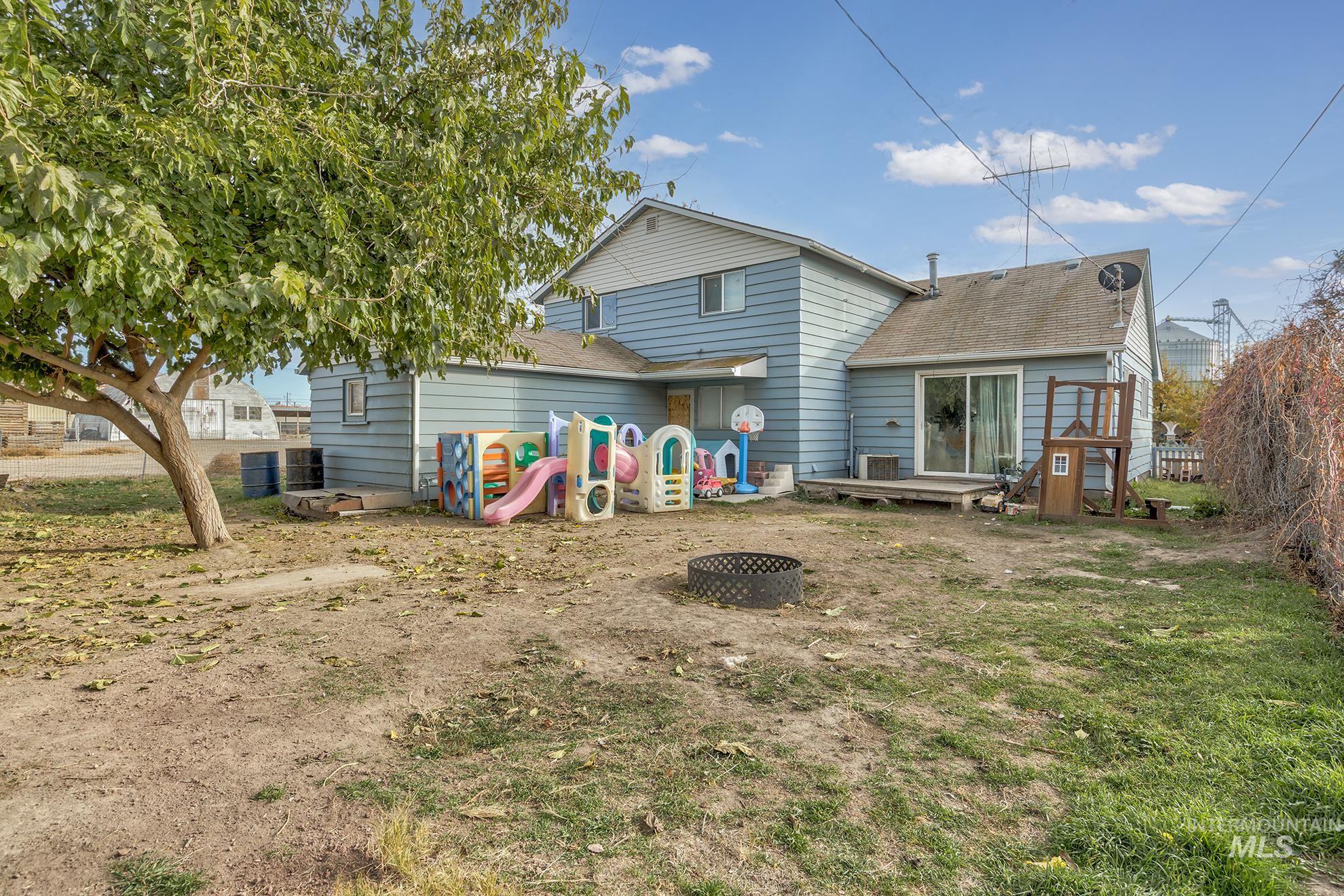 Rear view of house featuring roof with shingles, a fire pit, a deck, and a playground