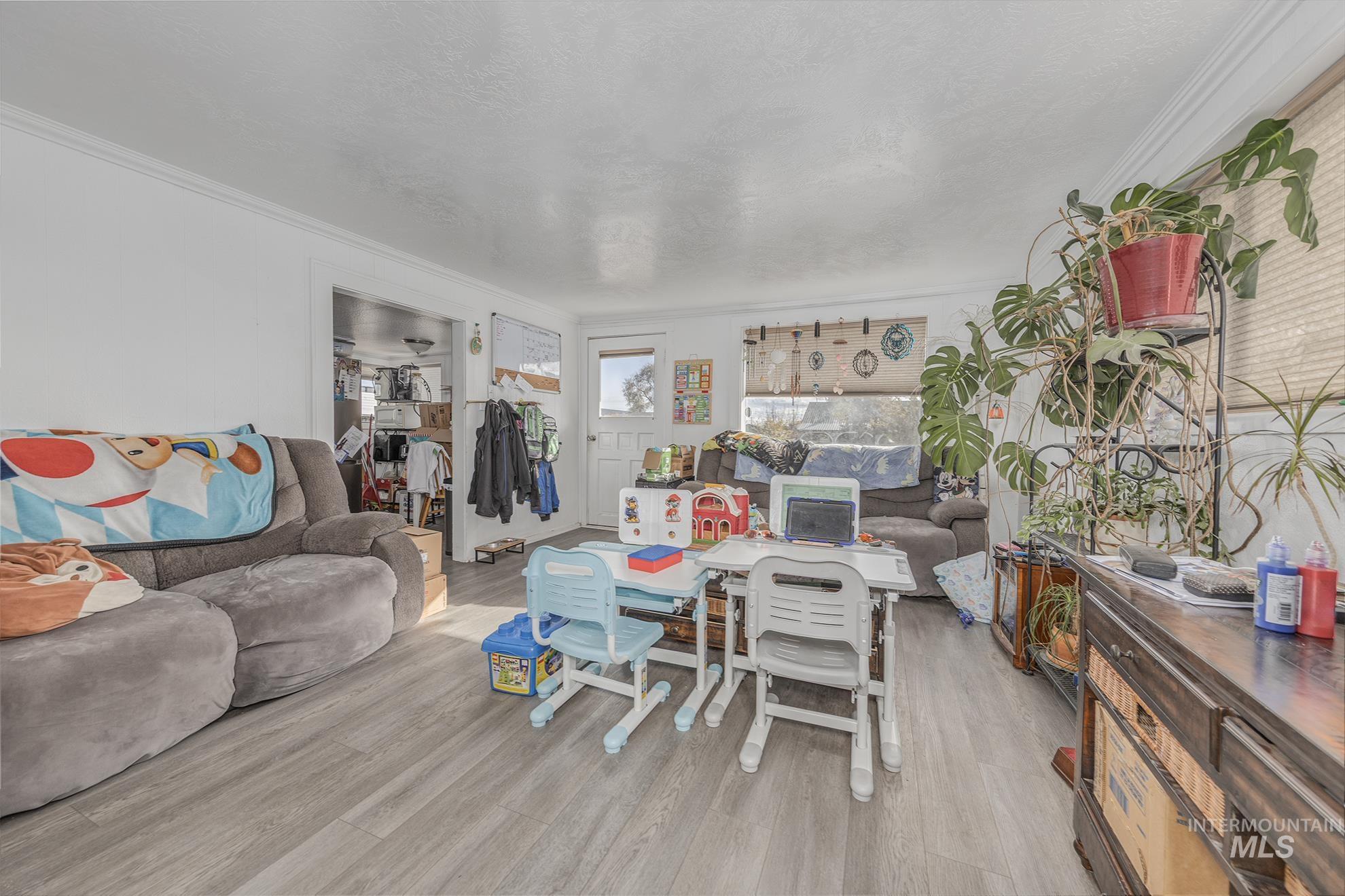 Living area featuring wood finished floors, crown molding, and a textured ceiling